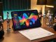 Illustration réaliste d’une tablette musicale entourée d’avatars générés par intelligence artificielle et de documents de licence dans un home studio moderne.